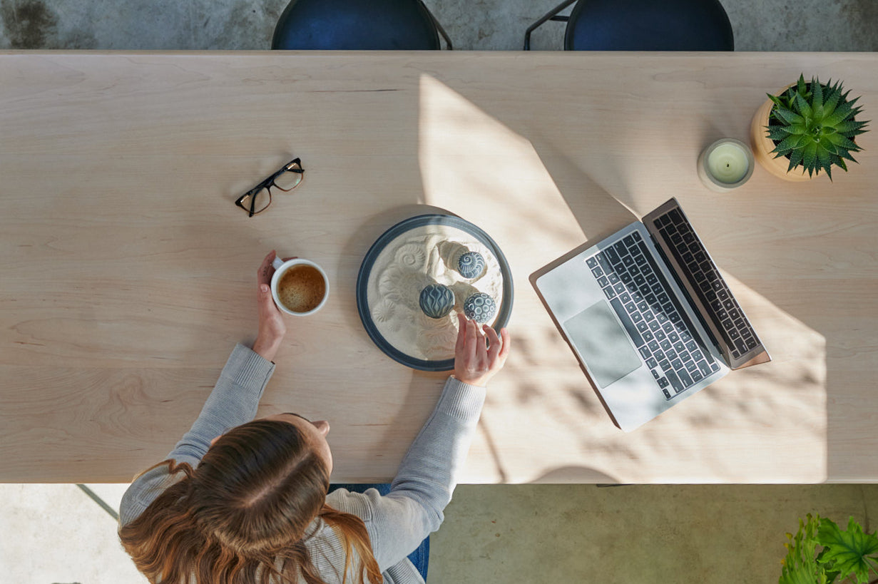 calm woman exploring coastal inspired desktop sand play while working and enjoying her morning coffee